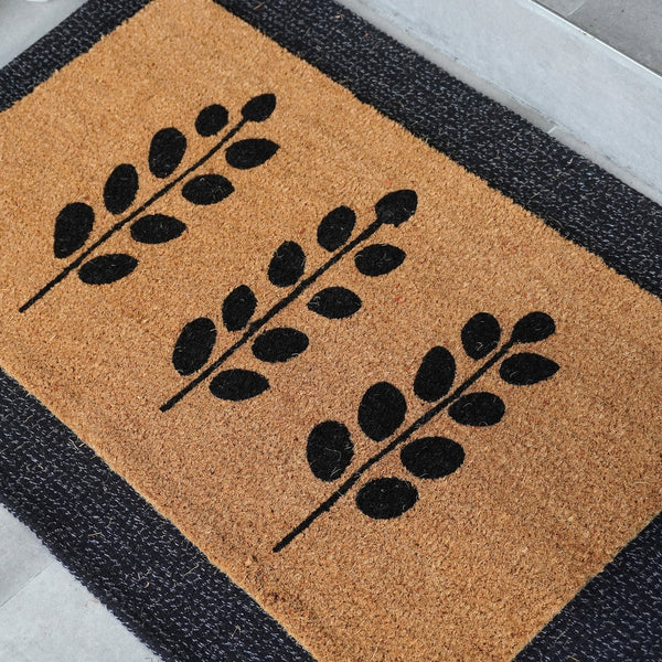 Silhouette Garden doormat featuring three bold leaf silhouettes woven into natural coir, shown