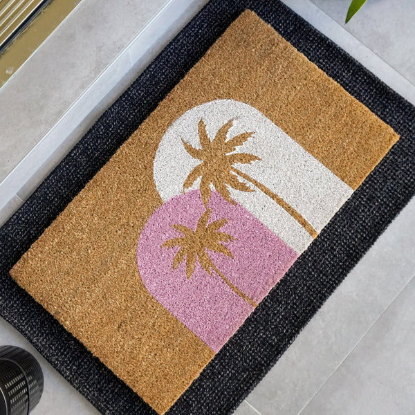 Sunset Palms natural coir doormat featuring soft pink and white arches with palm tree silhouettes