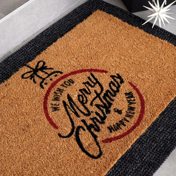 Christmas doormat featuring Merry Christmas script in circular design with decorative bow, natural coir fiber with red and bl
