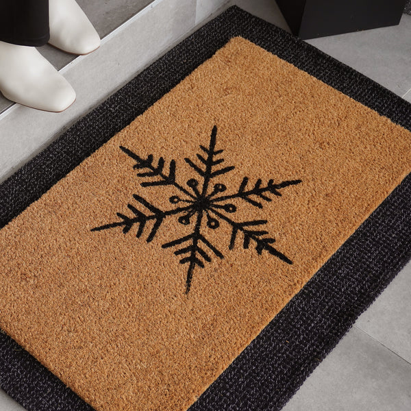 Snowflake natural coir doormat with bold black snowflake design on tan background