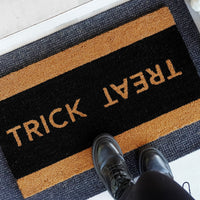 Trick or Treat Halloween doormat in natural coir with black center and natural border, shown [at front door/on porch/detail o